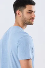 Remera azul marino de manga corta con cuello redondo, confeccionada en mezcla de algodón y poliéster. Presenta un diseño en el frente que combina estampa y bordado con la leyenda "Legacy Brand 1972" en tonos rosado, verde y marrón.