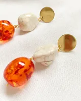 Aros colgantes con base dorada, cuenta de piedra sintética color crema y cuenta de resina traslúcida color naranja.