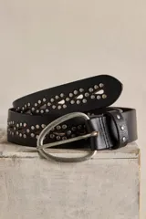 Cinturón de cuero negro con calados en forma de gota, detalles de tachas metálicas y hebilla ovalada de metal envejecido.