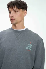 Buzo gris melange de corte clásico con cuello redondo y puños y cintura acanalados. Estampa pequeña en el pecho con la frase "Seek Inner Balance".