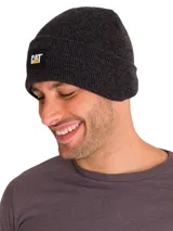 Gorro tipo beanie de punto acanalado en color gris oscuro, con vuelta en el borde y etiqueta rectangular con el logo de CAT en el frente.