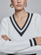 Sweater de tejido de punto con escote en V, de manga larga, color blanco con detalles de rayas en contraste color negro en el cuello y los puños.