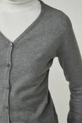 Cárdigan color beige con escote en V y cierre frontal con botones.