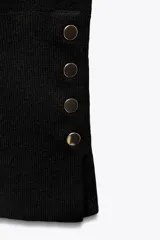 Jersey de punto liso con cuello redondo y manga larga. Presenta detalle de botones decorativos en los puños.