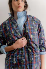 Campera reversible de estilo parka, color celeste, con diseño capitoneado con patrón de flores. Presenta ajuste elástico en la cintura, cuello alto y mangas largas. Incluye parche de marca en la parte superior de la espalda.