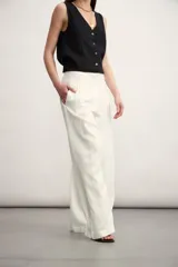 Pantalón de corte sastrero y tiro alto, con diseño de pierna ancha y pinzas frontales. Cuenta con bolsillos laterales y cierre frontal con botón oculto.