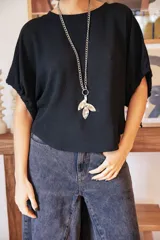 Collar de cadena de eslabones plateados con dije colgante de alpaca en forma de hoja con textura irregular. El diseño permite múltiples formas de uso.