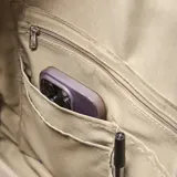 Mochila urbana de tela arrugada color beige, con múltiples compartimentos con cierre, bolsillos laterales y logo circular de la marca en el frente.