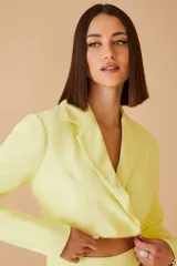 Blazer color amarillo con doble cierre dorado en la parte inferior.