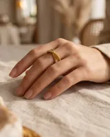 Anillo de bronce con acabado dorado, diseño entrelazado de líneas finas y textura acanalada.