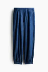Pantalón globo en denim de algodón con elástico en la parte posterior de la pretina, piernas amplias con pinzas, bolsillos al bies y bajos abotonados.