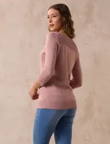 Buzo color rosa de tejido combinado con detalle de botones en las mangas y cuello redondo.