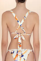 Top de bikini blanco con escote corazón y fruncido central. Presenta un estampado abstracto con pinceladas en tonos naranja, azul, rosa y negro. Tiene tirantes finos ajustables.