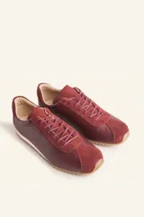 Zapatilla tipo runner color gris claro, de cuero y gamuza combinada, con suela de caucho blanca.