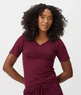 Blusa de pijama bordó de ribana, con textura acanalada, escote en V con abertura frontal de botones y mangas cortas.