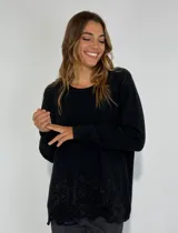 Sweater negro de punto con cuello redondo y detalle de flores bordadas en el ruedo.