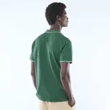 Remera polo de manga corta confeccionada en piqué de algodón color verde. Presenta cuello y bordes de mangas con detalle de línea blanca en contraste, y escote en V sin botones.