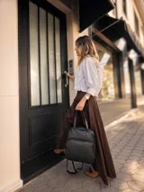 Mochila versátil convertible en cartera, color beige con detalles en marrón. Cuenta con doble asa superior, correas ajustables y desmontables, bolsillo frontal con cierre y compartimento principal amplio.