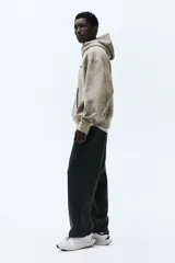 Pantalón de jogging negro de corte estándar, confeccionado en tejido de punto pesado. Presenta cintura elástica con cordón ajustable, bolsillos laterales y diseño de piernas rectas.