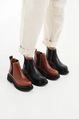 Botas tipo chelsea de cuero con suela track dentada y paneles elásticos laterales. Presentan costuras a contratono y tirador en la parte trasera.