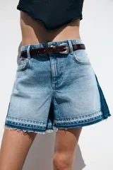 Shorts de jean de tiro medio, corte mom fit, con efecto lavado y terminación desflecada. Presenta cinco bolsillos y cierre frontal con cremallera y botón.