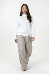 Polera de cuello alto y manga larga, confeccionada en algodón suave de color blanco, con diseño de corte recto y aberturas laterales en el ruedo.