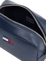 Cartera bandolera de poliuretano azul marino, de diseño compacto tipo cámara, con cierre superior, correa ajustable y logo engomado de Tommy Jeans en el frente.