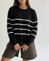 Sweater de tejido Bremer con diseño a rayas horizontales negras sobre base color crema, de corte holgado, cuello redondo y mangas largas con puños acanalados.