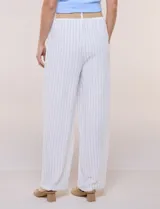 Pantalón wide leg blanco con finas rayas verticales oscuras, tiro alto, bolsillos laterales y pinzas frontales. Incluye un cinturón trenzado de rafia con hebilla rectangular.