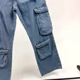Pantalón jean celeste, corte holgado, con múltiples bolsillos tipo cargo en los laterales.