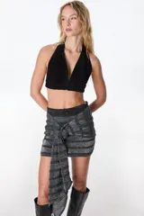 Top corto negro de cuero con escote halter y espalda descubierta.