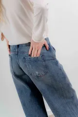 Pantalón de jean color naranja con tiro medio, diseño de pierna ancha y cinco bolsillos. Presenta costuras con pespuntes a contratono.