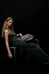 Chaleco largo de vestir, color marrón oscuro jaspeado, con cuello redondo, cierre frontal de botones y bolsillos ribeteados. Presenta un corte entallado y forro interior.