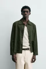 Sobrecamisa de hombre con cuello solapa, manga larga y cierre frontal de botonadura. Presenta un estampado de rayas verticales en tonos de verde oliva y verde oscuro. Incluye bolsillos plastrón en la cadera.