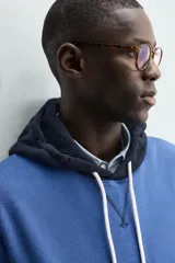 Sudadera hoodie regular fit de color azul, con capucha y bolsillo canguro negro. Cuenta con cordones ajustables blancos y detalles en color negro en la capucha, el bolsillo y los puños.