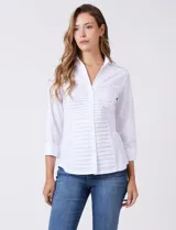 Camisa blanca entallada de algodón con escote en V y cuello con solapa. Presenta un diseño frontal con alforzas horizontales en la pechera y mangas tres cuartos con puños anchos rebatibles.