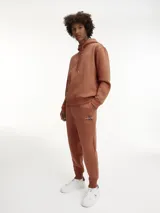 Pantalón de chándal color marrón, de corte regular, con cintura elástica con cordón, puños de canalé, bolsillos laterales y bolsillo trasero.