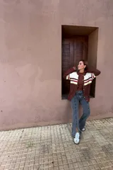 Saco tejido de punto con diseño de ochos, con bloques de color en marrón, blanco, rojo y amarillo neón. Presenta mangas largas y cierre frontal con botones.