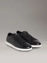 Zapatillas urbanas Calvin Klein de perfil bajo, color negro con suela blanca y detalle beige en el talón. Confeccionadas en cuero granulado, cuentan con cordones negros y el monograma de la marca grabado en el lateral.