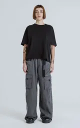 Pantalón cargo de corte oversize y pierna recta, color grafito. Cuenta con cintura elastizada, cinturón integrado con cinta de seguridad, múltiples bolsillos laterales con solapa y detalles reflectivos.