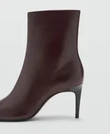 Botin de cuero caprino color marrón oscuro, con diseño de punta fina y tacón kitten de 6,5 cm. Cuenta con cierre de cremallera lateral.