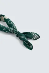 Bandana cuadrada confeccionada en tejido fluido de lyocell, color bordó con estampado en contraste beige. Presenta un diseño central de cuadros rodeado de motivos abstractos y caligrafía.