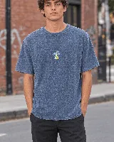 Remera blanca de algodón peinado, de corte recto y mangas cortas, con un pequeño estampado artesanal en el pecho que representa un hongo con elementos faciales.