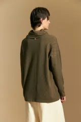 Polera de tejido de punto color naranja con cuello alto de caída relajada y diseño de líneas en relieve. Presenta una silueta holgada con hombros caídos y mangas largas.