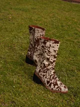 Botas de caña media con estampado animal print tipo vaca, taco ancho y punta redondeada. Cuenta con cierre lateral y diseño de pelo sintético.