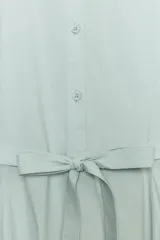 Vestido midi camisero de algodón color verde menta, con cuello camisero, manga abullonada por debajo del codo, cierre frontal con botones y lazo ajustable en la cintura.
