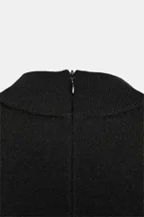 Vestido corto negro de tejido de punto, con cuello redondo alto y mangas anchas a la altura del codo. Presenta un corte entallado en la cintura y cierre con cremallera oculta en la espalda.