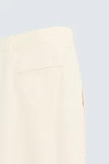 Bermuda de corte regular fit en color beige claro, confeccionada en una mezcla de algodón, lyocell y lino. Presenta pliegues frontales en la cintura, bolsillos laterales y traseros, y cierre frontal con cremallera y botón.
