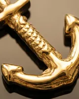 Dije en forma de ancla con baño de oro, de diseño náutico clásico.