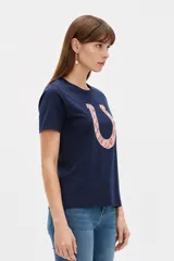 Remera blanca de manga corta y cuello redondo, confeccionada en algodón, con un diseño holgado y estampado frontal de estrella roja con textura y detalles de estrellas pequeñas.